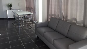 A modern living room with a grey sofa, a dining table with chairs, and a painting on the wall. - 180 ° sea view apartment in Carry le Rouet (Carry-Le-Rouet)