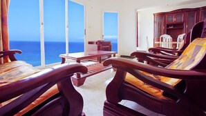 Een kamer met uitzicht op zee, houten meubels en een kast.