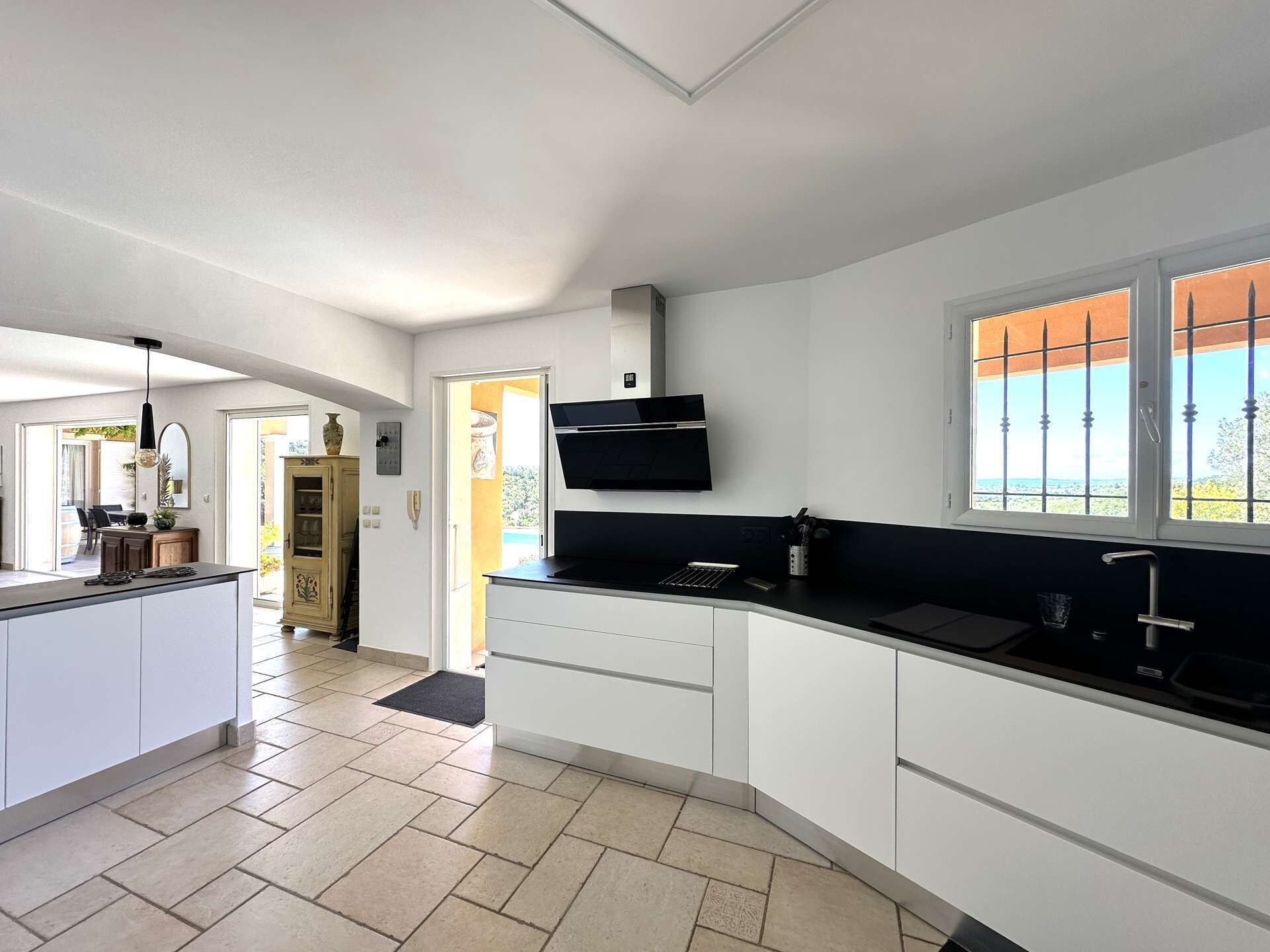 A modern kitchen with white cabinets, a black countertop, and a built-in stove. There is a window with a view of the outdoors.