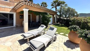 A house with a patio area featuring lounge chairs and a pergola.