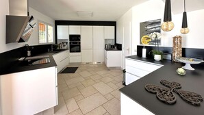 A modern kitchen with white cabinets, a black countertop, and pendant lighting.