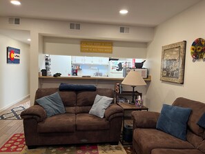 A living room with two brown sofas, a coffee table, and a kitchen in the background.