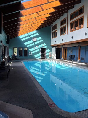 A swimming pool with a sunlit interior, a door, and a seating area with chairs. - Updated MountainSide Condo in The Heart of Frisco! (frisco)