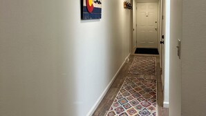 A hallway with a wooden floor, a colorful rug, and a wall-mounted artwork. - Updated MountainSide Condo in The Heart of Frisco! (frisco)