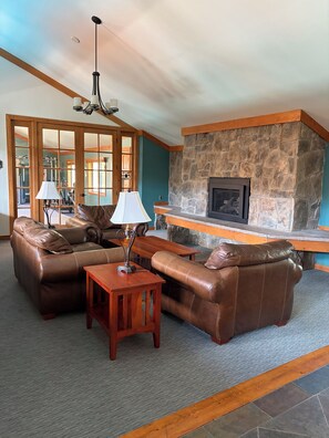 A spacious living room with leather sofas, a wooden coffee table, and a stone fireplace. - Updated MountainSide Condo in The Heart of Frisco! (frisco)
