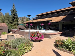A patio area with outdoor seating, a hot tub, and a pathway leading to a building with a sloped roof. - Updated MountainSide Condo in The Heart of Frisco! (frisco)