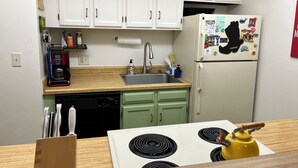 A compact kitchen with white cabinets, a stainless steel sink, a coffee maker, a dishwasher, and a refrigerator with magnets. - Updated MountainSide Condo in The Heart of Frisco! (frisco)