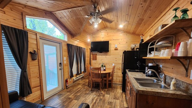 A cozy cabin interior with a dining area, kitchen, and seating area. - Christopher Creek Cabins - Cabin 5 (Payson)