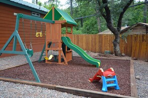 Children can play on the wooden play structure with a slide and swing set.