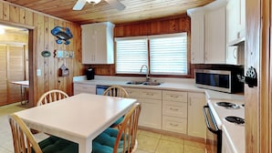 A compact kitchen with wooden cabinets, a white countertop, a microwave, and a stove. - Whitaker Sea La Vie | Soundfront Property, Great Views! (Topsail Beach)