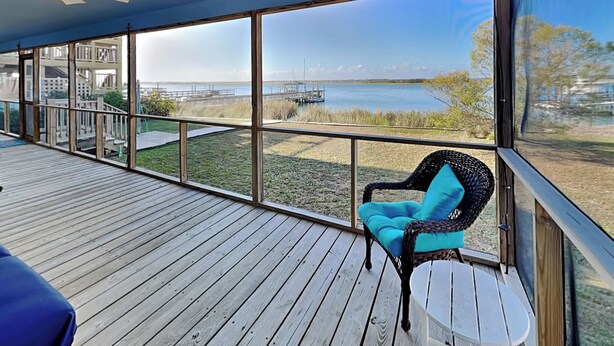 A covered deck with a view of a lake and a dock. - Whitaker Sea La Vie | Soundfront Property, Great Views! (Topsail Beach)