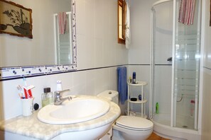Une salle de bain équipée d’un lavabo, de toilettes et d’une douche à parois de verre.
