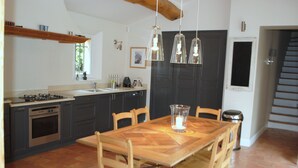 A kitchen with a large wooden table, chairs, a stove, and hanging pendant lights. - Provencal farmhouse from the 19th century with swimming pool, charming house (Aix-En-Provence)