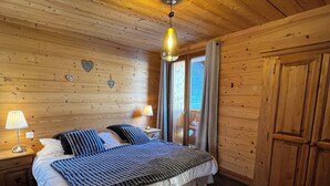 Une chambre dans une cabane en bois, avec un lit, des tables de chevet et un luminaire suspendu.