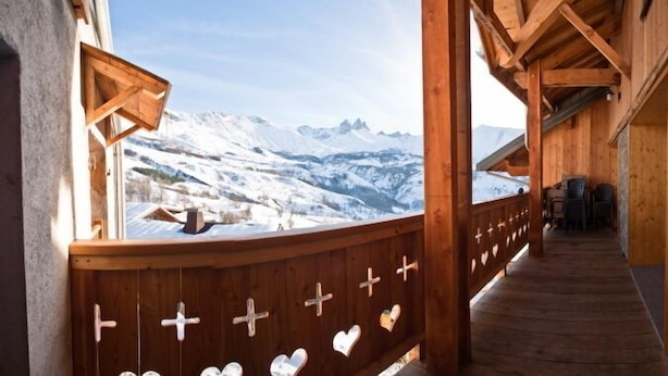 Un balcon en bois offrant une vue sur des montagnes enneigées.