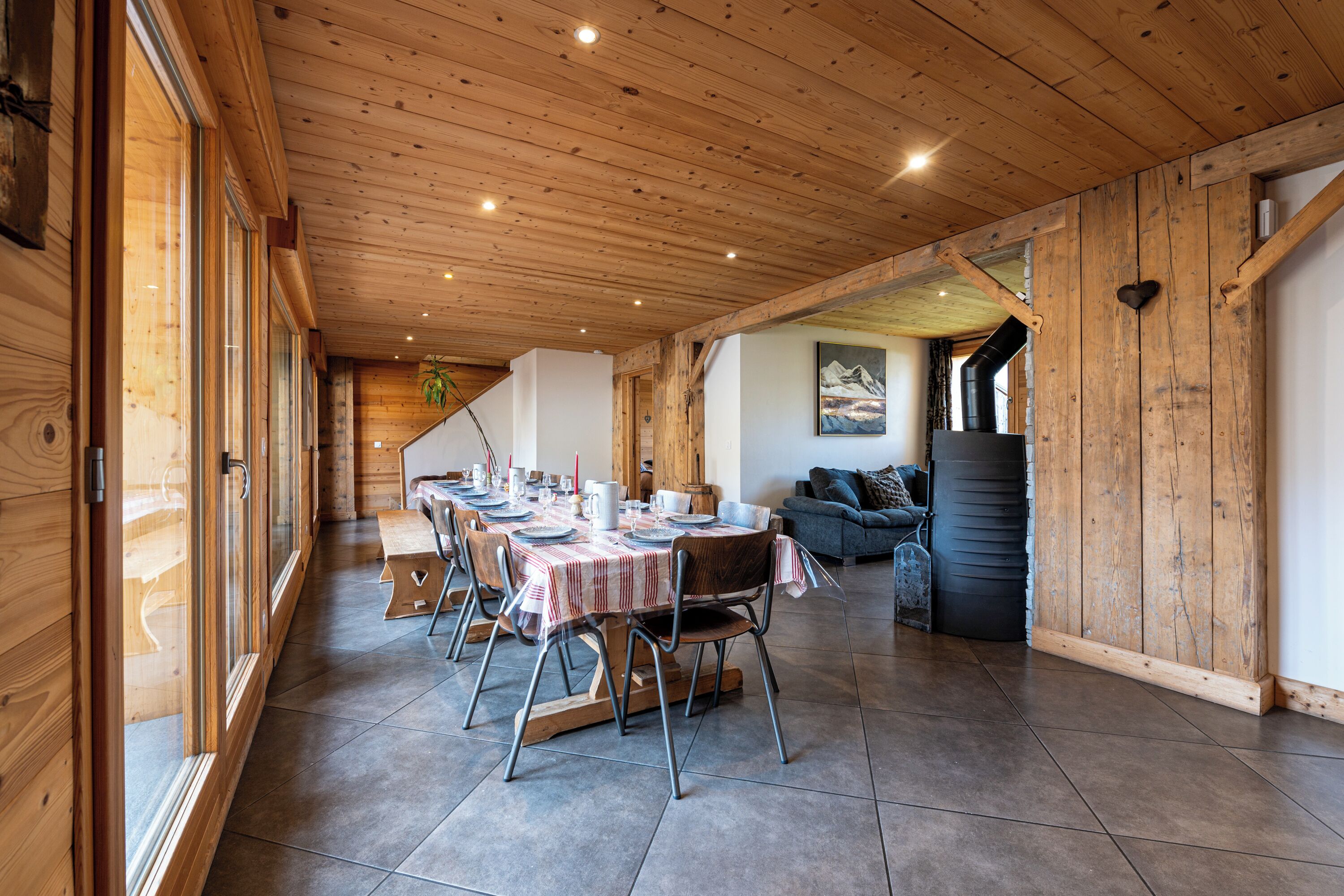 A wooden interior with a dining area, a sofa, and a staircase.