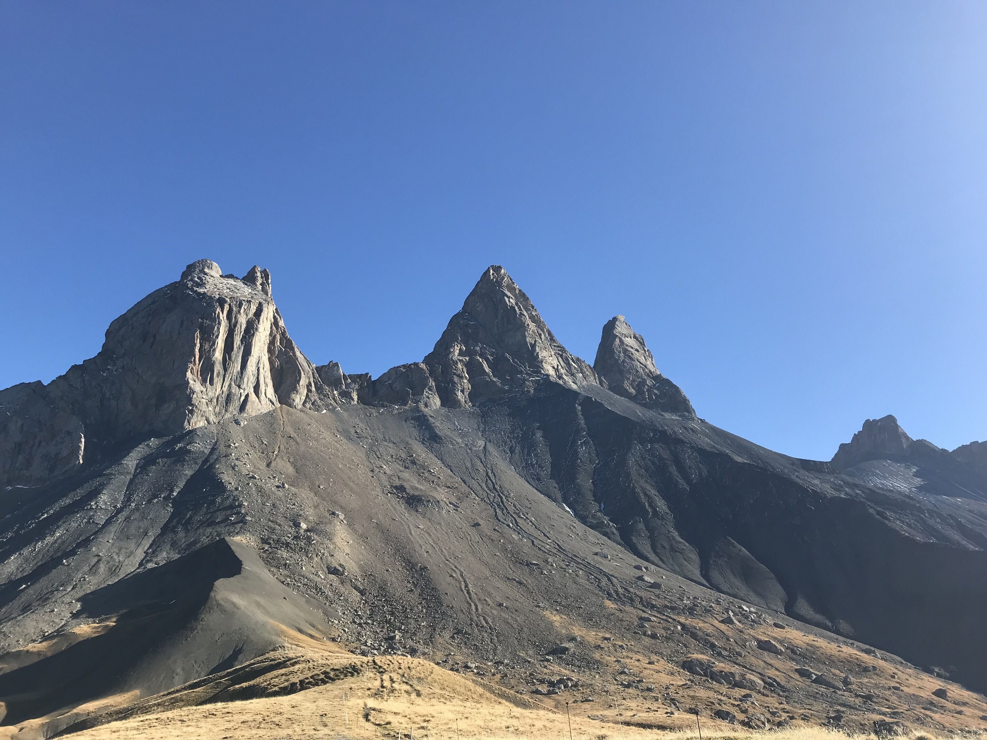 Et barskt bjerglandskab med spidse toppe og en klar blå himmel.
