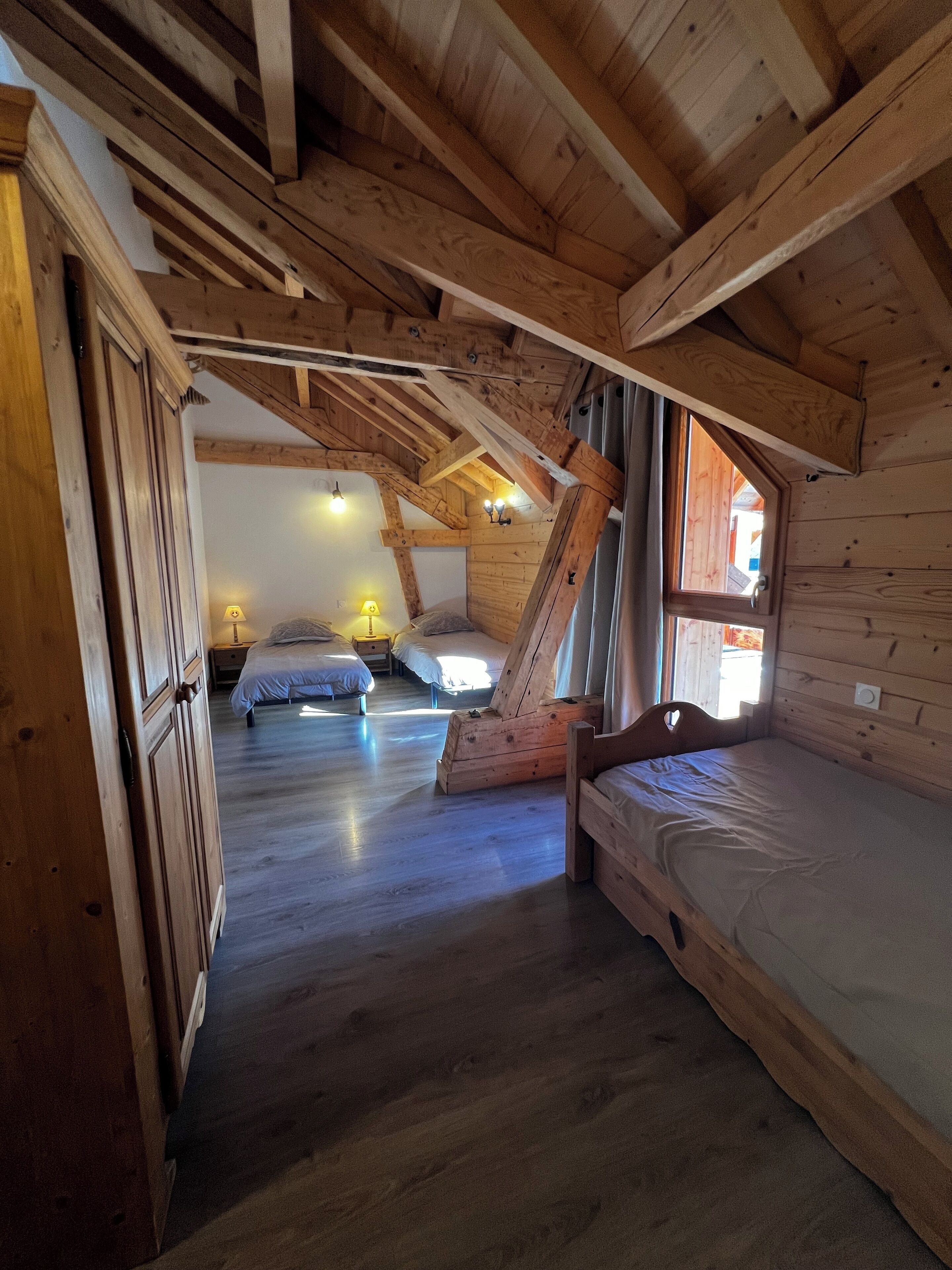 Una cabaña de madera con habitación en altillo, cama en altillo y un ventanal grande.
