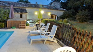 A poolside area with lounge chairs, a table, and a yellow umbrella.