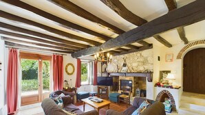 A cozy living room with exposed wooden beams, a stone fireplace, and comfortable seating.