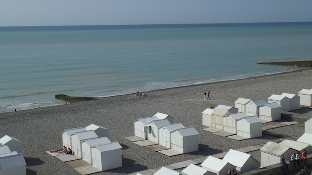 Ein Strand mit weißen Strandhütten und freiem Blick auf das Meer.
