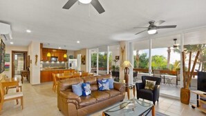 A spacious living area with a leather sofa, glass coffee table, and a dining area with wooden furniture. - Corner Unit in the Building That (San Miguel)