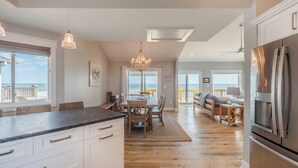 Een moderne keuken met een groot keukeneiland, houten vloeren en uitzicht op de oceaan.