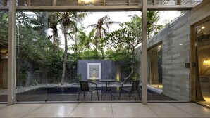 A modern indoor garden with a glass wall, a wooden table, and two chairs.