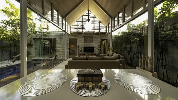 A modern living room with a large TV, comfortable seating, and a dining area with a unique table design.