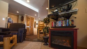A cozy living room with a fireplace, a bookshelf, and a Christmas tree. - Luxury Apt,  Private Hot Tub, Couples Retreat (Breckenridge)