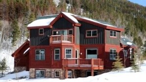 A multi-story lodge with a balcony, set against a snowy mountain backdrop. - Luxury Apt,  Private Hot Tub, Couples Retreat (Breckenridge)