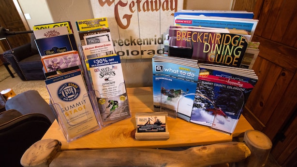 A wooden table with various travel brochures and a small sign. - Luxury Apt,  Private Hot Tub, Couples Retreat (Breckenridge)