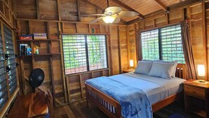A wooden cabin room with a bed, a desk, and a chair. - Baby Blue Cabana (Hopkins Village)