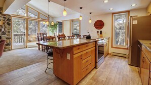 A spacious kitchen with a large island, wooden cabinets, and a stone accent wall.