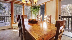 A wooden dining table with chairs, a bowl of fruit, and a hanging plant.