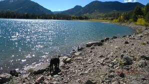 Un lago con orilla rocosa y montañas al fondo.