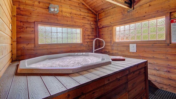 Una cabaña de madera con un jacuzzi, dos ventanas con vidrio esmerilado y un grifo de metal.