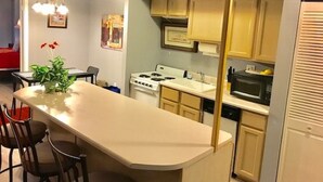 Eine kompakte Küche mit Kochinsel, Herd, Mikrowelle und Spüle.