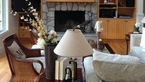 Una sala de estar con chimenea de piedra, televisor y estantería.