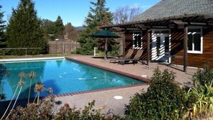 Un patio trasero con piscina, terraza de madera y zona de patio cubierta.