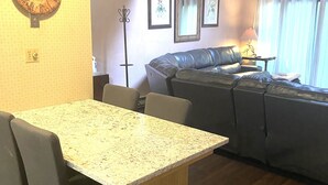 Ein Wohnzimmer mit Esstisch, Ledersofa und einer Wanduhr.