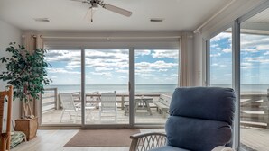 A room with a view of the beach, a ceiling fan, and a large window. - Mamaw's Spot | Oceanfront + Pet Friendly! (Topsail Beach)