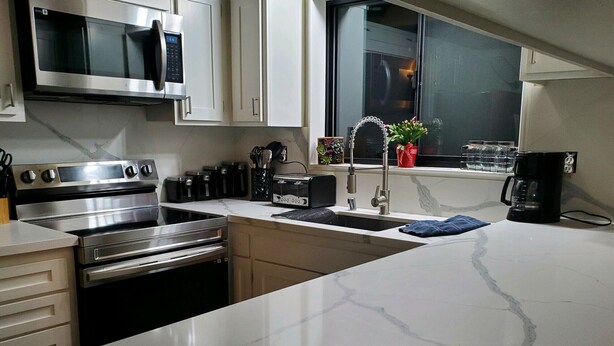 Una cocina moderna con electrodomésticos de acero inoxidable, encimera de mármol y ventana con vistas.