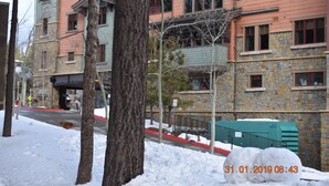 Un edificio de varios pisos con fachada de piedra y marcos de ventanas rojos.