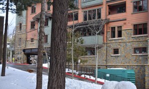 Un edificio de varios pisos con fachada de piedra y marcos de ventanas rojos.