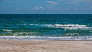 Ein Strand mit klarem, blauem Wasser und sandigem Ufer.