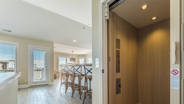 Eine moderne Wohnung mit Holzelevator, einer Küchenzeile mit Barhocker und Blick durch große Fenster nach außen.