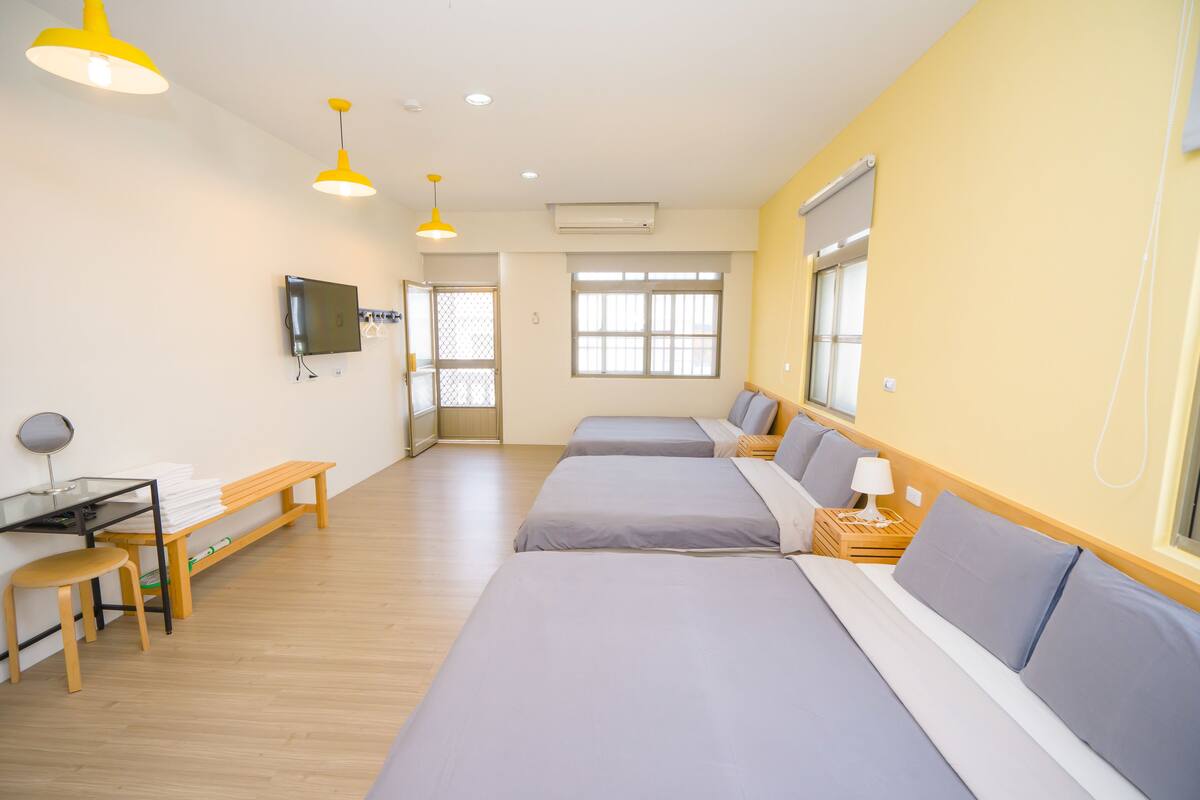 A hotel room with two beds, a desk, and a TV.