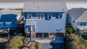 Une maison à deux étages avec un quai, située près d’une plage.