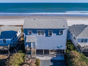 A two-story house with a dock, located near a beach.